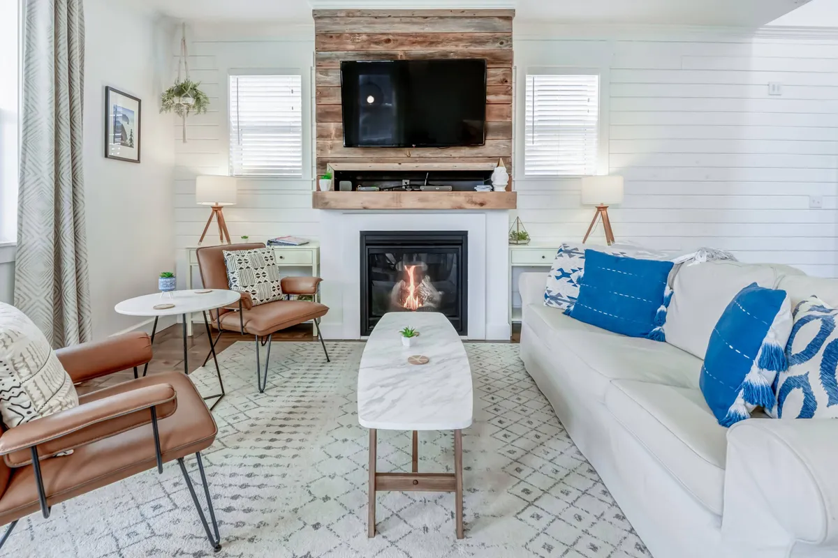 A warm, welcoming interior scene featuring a sofa facing a fireplace and a TV, with coffee tables set for group activities. The space is designed for relaxation and entertainment, ideal for movie nights, gaming, or gathering with friends.