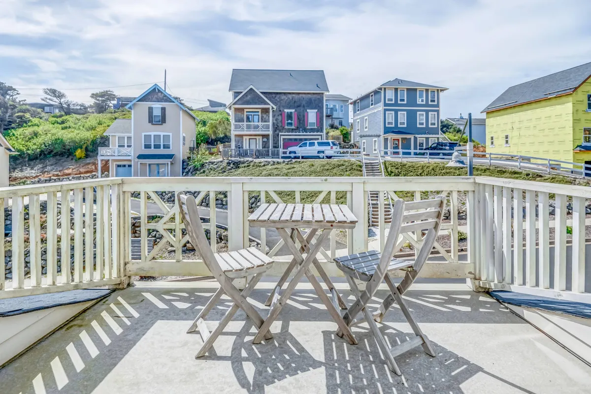 A peaceful balcony scene featuring a small table and two chairs, with a view of surrounding houses. The setting invites moments of relaxation, such as enjoying morning coffee or peaceful evenings, and hints at the neighborhood's walkability and friendly atmosphere.